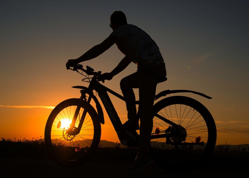 Mann auf E-Moutainbike Offroad im Sonnenuntergang