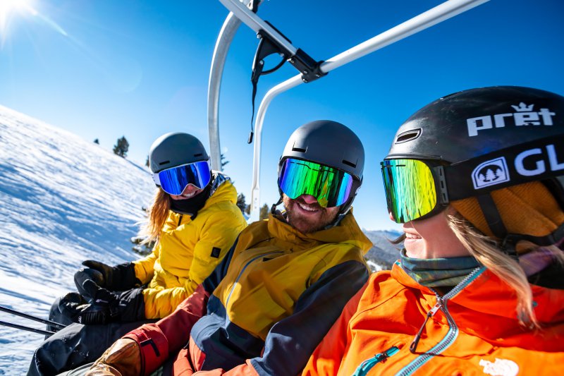 Skifahrer tragen Skibrillen und sitzen im Skilift.