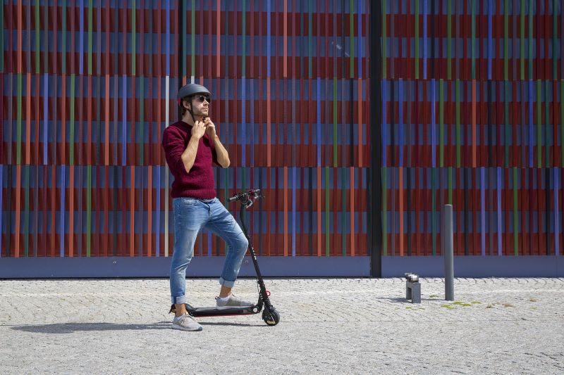 Mann mit E-Scooter und Helm