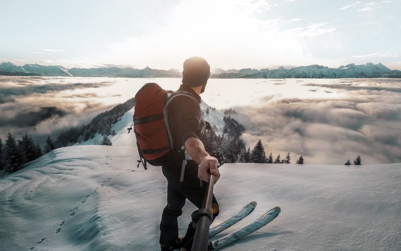 Mann mit Skirucksack im Schnee in den Bergen auf Skiern