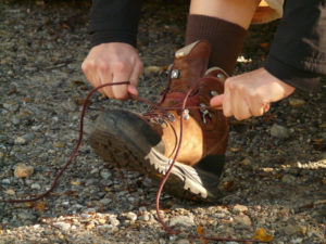 Person schnürt einen Wanderschuh