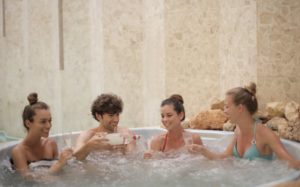 Freunde sitzen gemeinsam im aufblasbarem Whirlpool