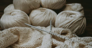 Zwei Strumpfstricknadeln und beige Wolle