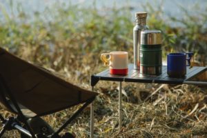 Thermoskannen auf einem Tisch beim Campen am See