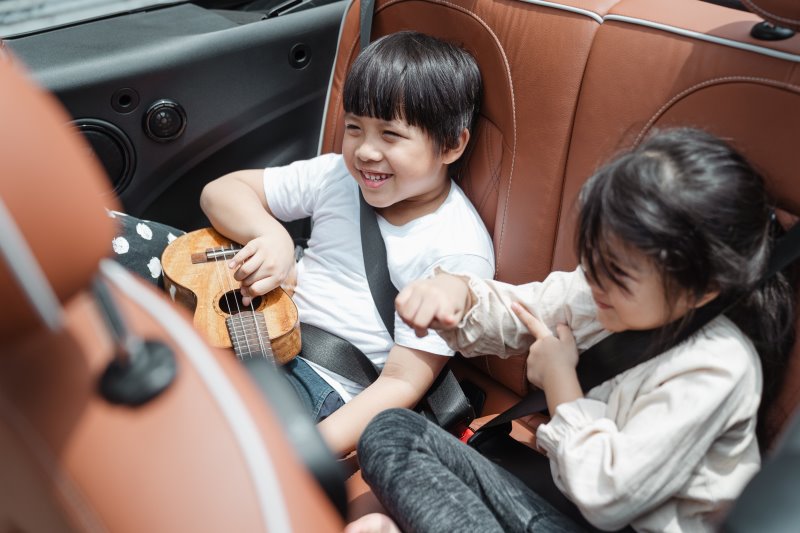 Kinder sitzen hinten in einem Auto und haben Spaß.