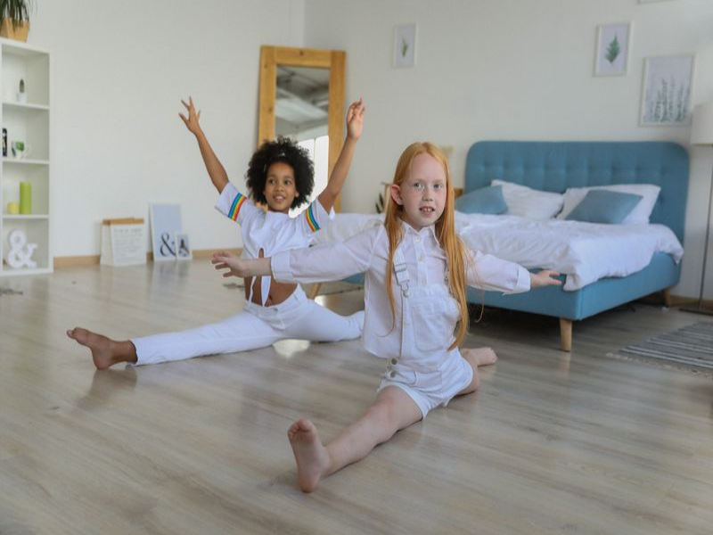 Zwei Kinder machen Spagat in einem Zimmer