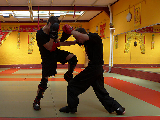Zwei Personen beim intensiven Sparringstraining in einer traditionellen Kampfsportschule