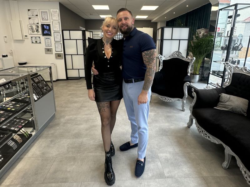Ein Tattoo-Studio-Team steht zusammen in einem gut eingerichteten Studio, umgeben von modernen Möbeln.