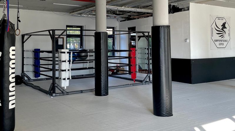 Moderner Trainingsbereich mit Boxring und Sandsack in einer Kampfsportschule.
