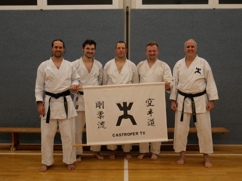 Karateka in traditioneller Kleidung nach dem Training mit Banner
