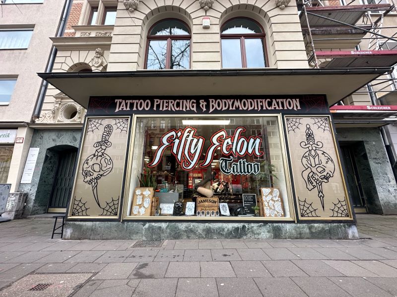 Außenansicht eines Tattoo-Studios mit auffälligem Schaufensterdesign und kreativen Illustrationen.